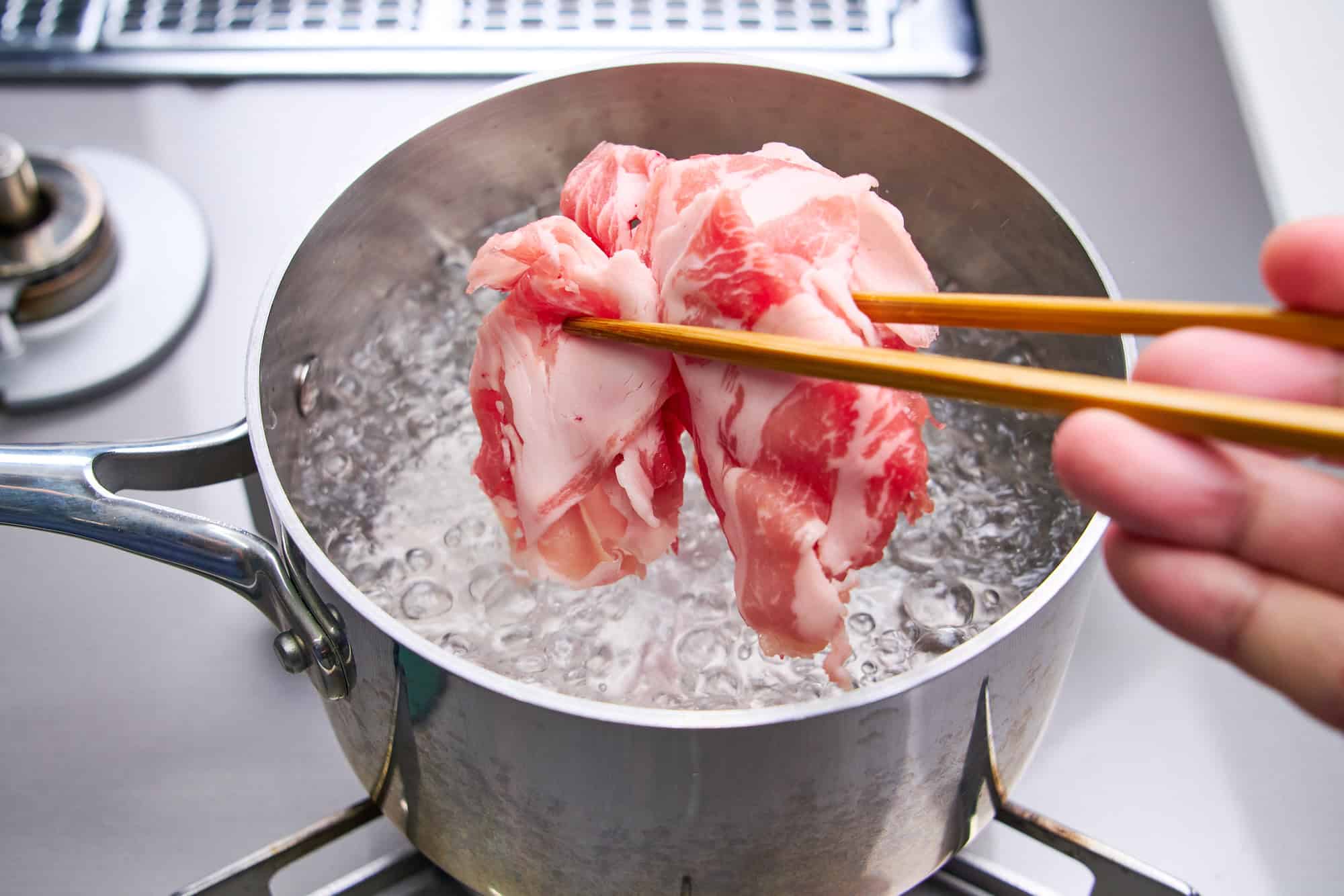 Lowering the pork slices into boiling water.