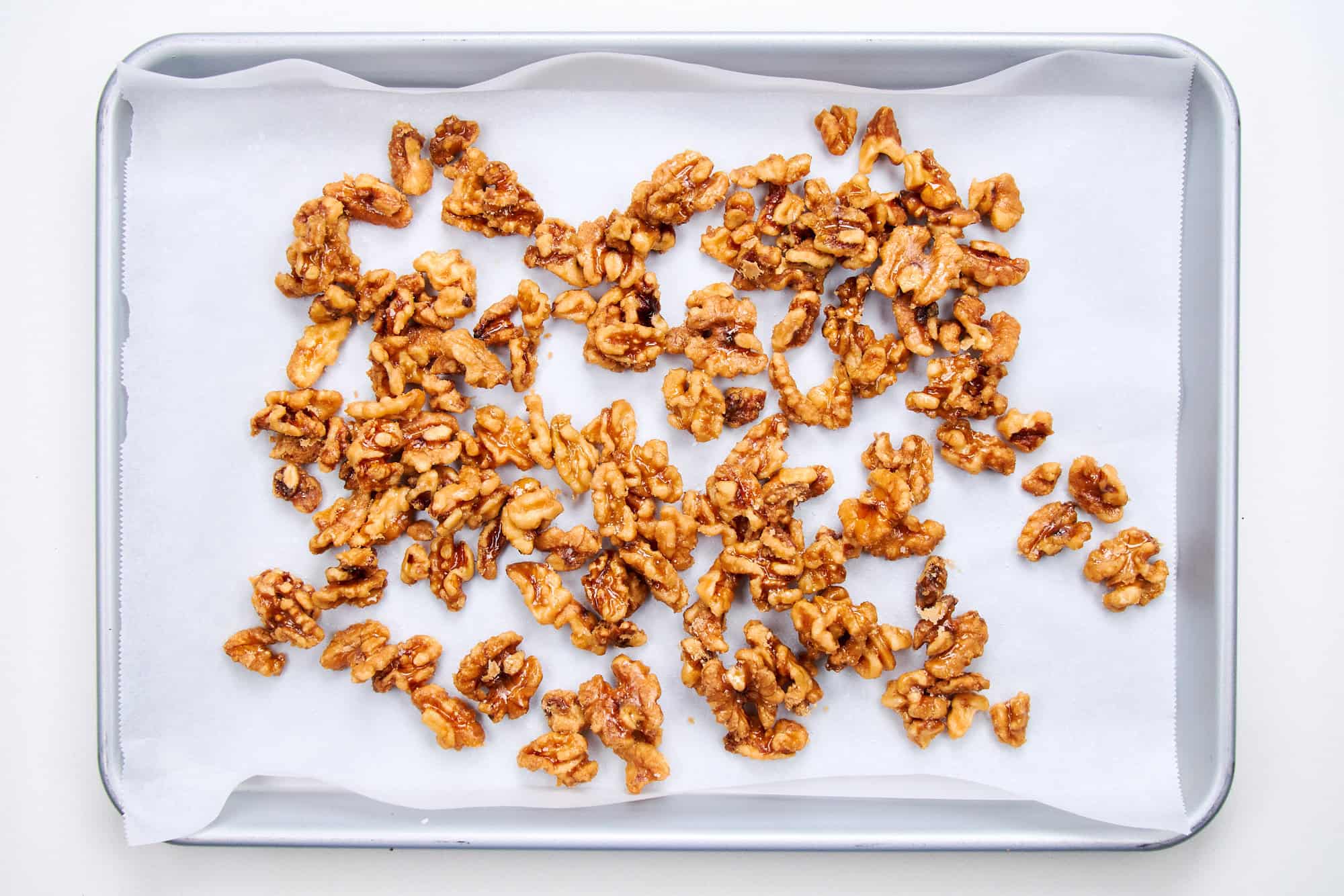 Candied walnuts cooling on parchment paper.
