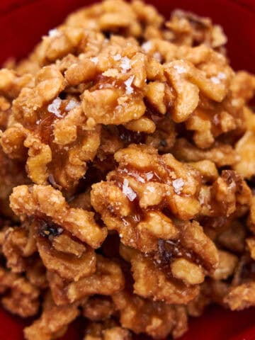 Maple Candied Walnuts arranged in a red lacquer bowl.